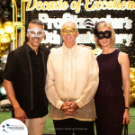 Three people wearing masks pose together at an event celebrating Profitmaster's 30th anniversary. A sign in the background reads "Decade of Excellence." .