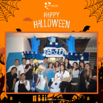 Group of people in Halloween costumes pose in front of a "Frozen"-themed backdrop with a "Happy Halloween" sign above.