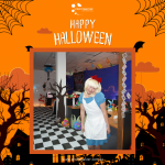 Person wearing a blue dress and white apron, posing in a decorated room with Halloween theme, spider webs, and "Happy Halloween" text.