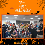 Group of people in costumes pose in an office setting for a Halloween event.