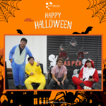 Four people in Halloween costumes sit and stand in front of a decorated backdrop with Halloween motifs.