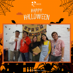 Five people posing in front of a "Happy Halloween" banner, with orange and black festive decorations and graphics around them.