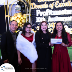 Four individuals stand together at an event. One holds a prize labeled "Staycation with Cash." A decorative backdrop with gold and black balloons and a sign reading "Profitmaster 10th Anniversary" is behind them.