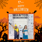 Three people in costumes pose in front of a "Wanted" backdrop with posters. The design features Halloween-themed graphics and text.