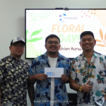 Three men in floral shirts smiling in front of a screen displaying "Floral Day Fashion Runway" with the Profit Master logo.