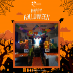 Office decorated for Halloween with string lights, colorful banners, and orange-themed decor. Background features Halloween graphics and festive text.