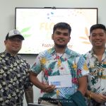 Three men wearing floral shirts stand in front of a screen displaying "Floral Day" branding.