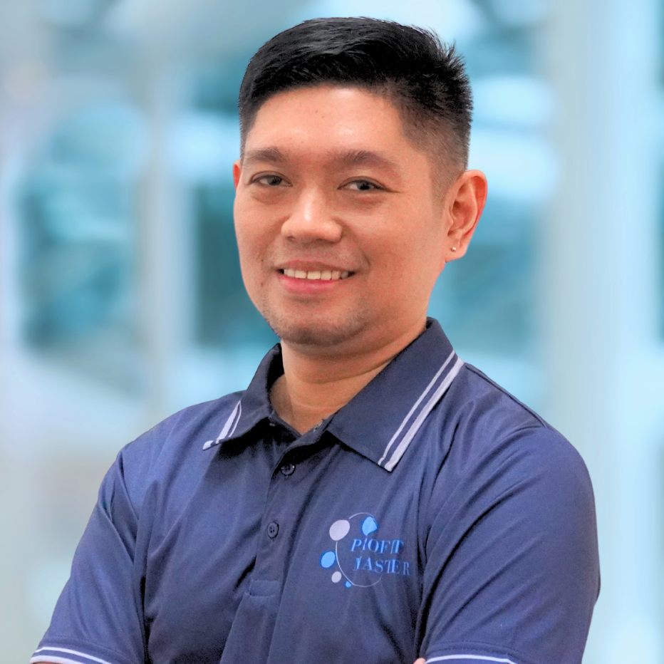 A person from our team, wearing a navy blue polo shirt with a "Profit Master" logo, smiles confidently while standing with arms crossed in front of a blurred background.