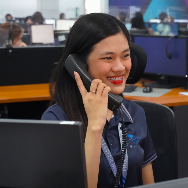 Woman in an office discusses bookkeeping, smiling while seated at a desk with a computer.